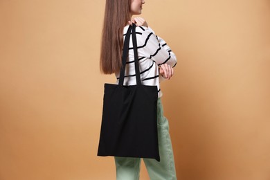 Photo of Woman with blank shopper bag on beige background, closeup. Mockup for design