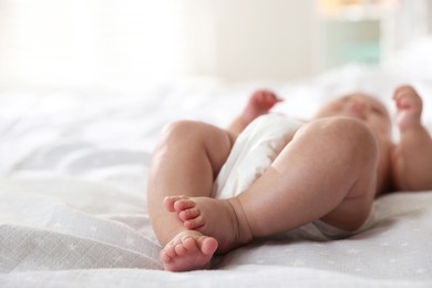 Photo of Cute little baby in diaper on bed indoors, selective focus. Space for text