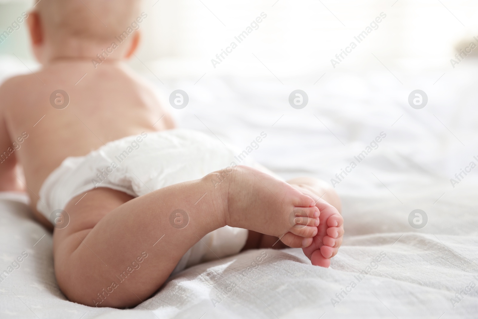 Photo of Cute little baby in diaper on bed, selective focus