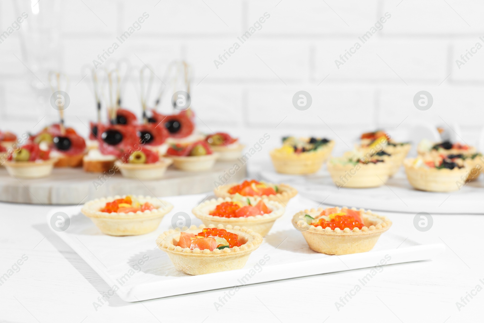 Photo of Many different tasty canapes on white wooden table, closeup