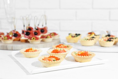 Photo of Many different tasty canapes on white wooden table, closeup