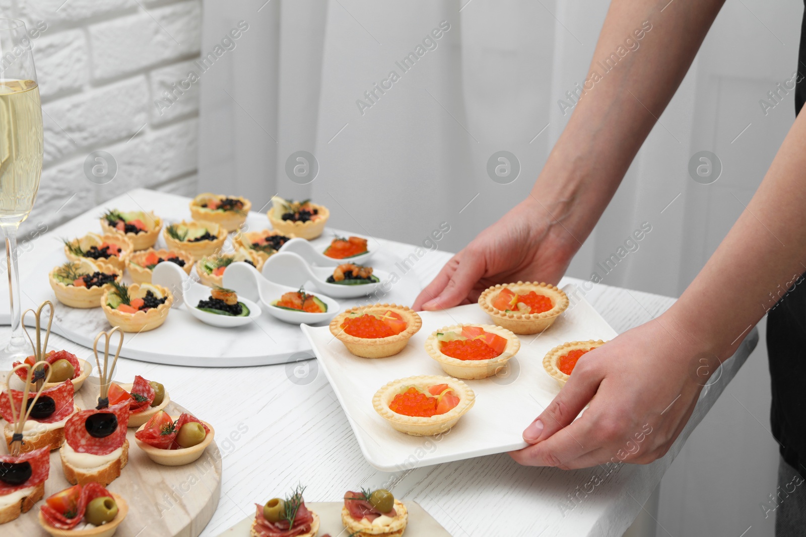 Photo of Woman with many different tasty canapes at white wooden table, closeup