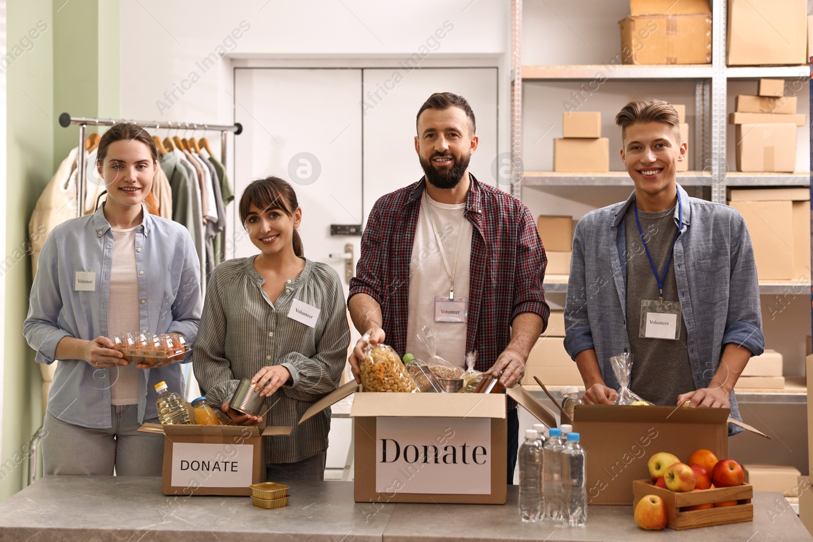 Photo of Group of volunteers packing food donations at table indoors