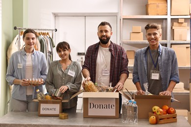 Photo of Group of volunteers packing food donations at table indoors