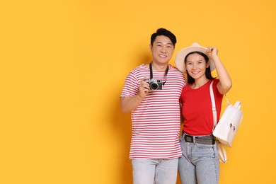 Photo of Happy travellers with camera on yellow background. Space for text