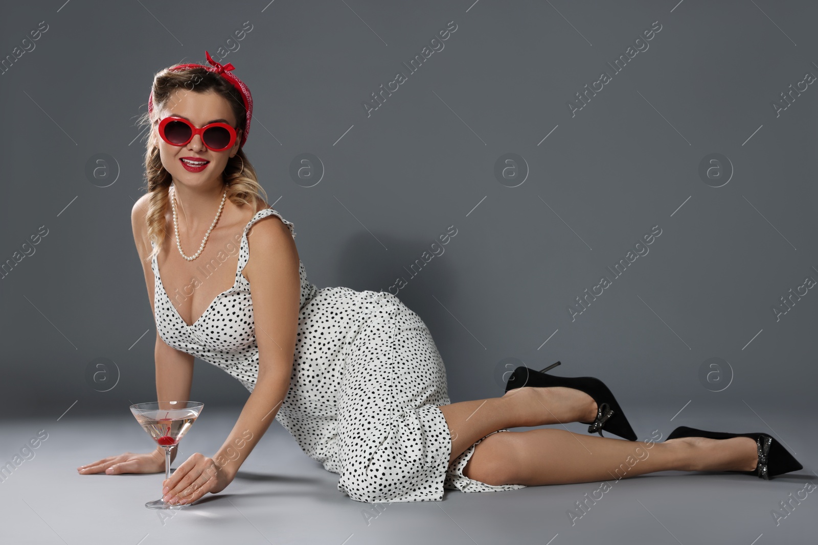 Photo of Happy pin-up woman with cocktail on grey background. Space for text