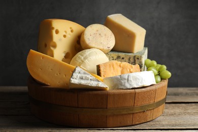 Photo of Different types of cheese and grapes on wooden table