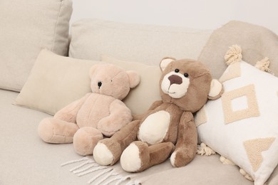 Photo of Two cute teddy bears and pillows on sofa in room