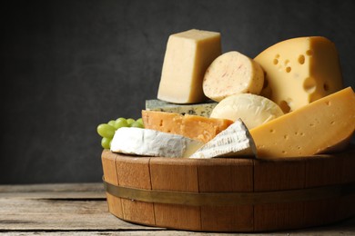 Photo of Different types of cheese and grapes on wooden table, closeup. Space for text