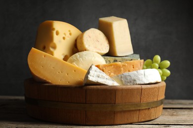 Photo of Different types of cheese and grapes on wooden table, closeup