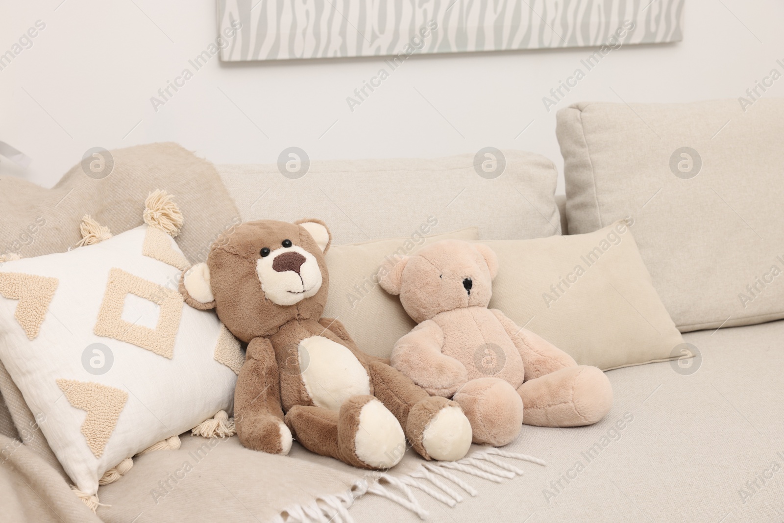 Photo of Two cute teddy bears and pillows on sofa in room