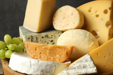 Photo of Different types of cheese and grapes on blurred background, closeup