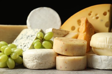 Photo of Different types of cheese and grapes on grey table, closeup