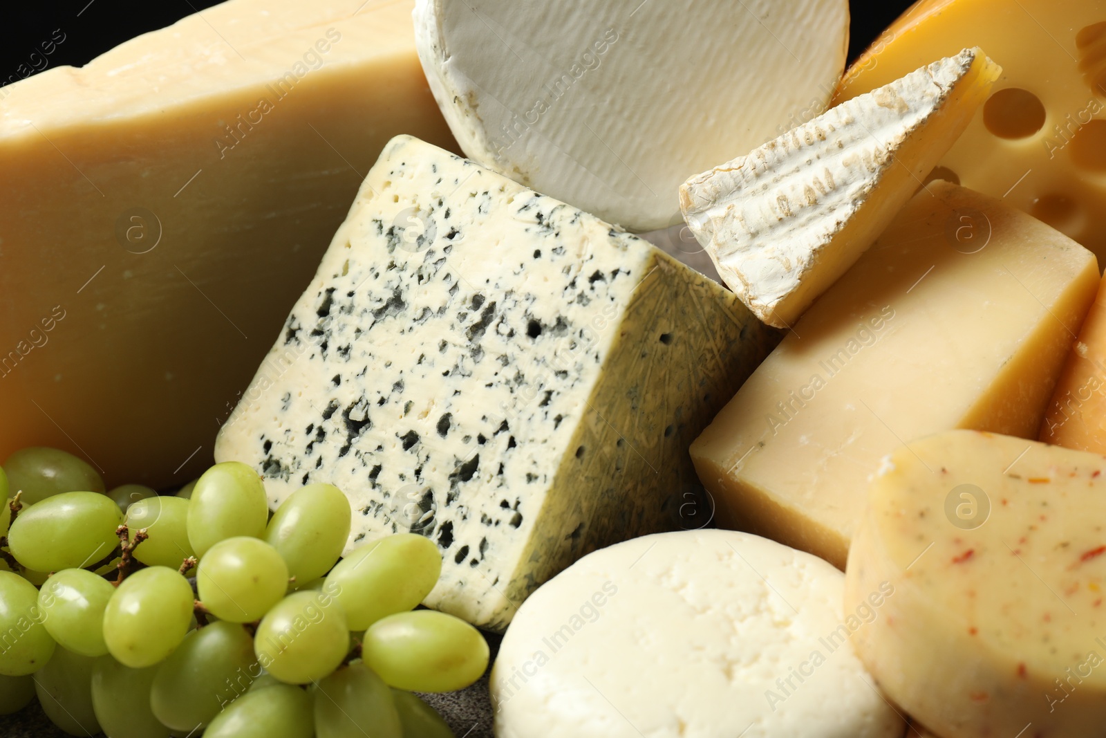 Photo of Different types of cheese and grapes on table, closeup