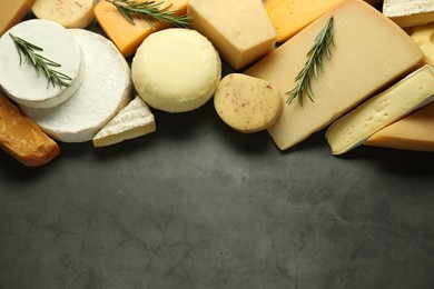 Photo of Different types of cheese and rosemary on grey table, flat lay. Space for text