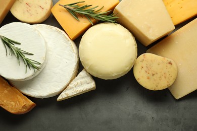 Photo of Different types of cheese and rosemary on grey table, flat lay