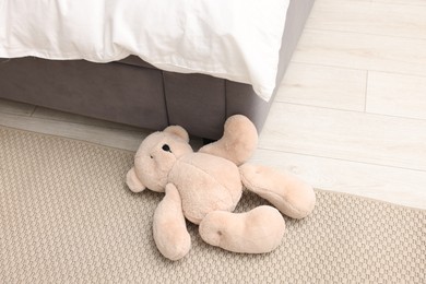 Photo of Lost teddy bear near bed on floor in room