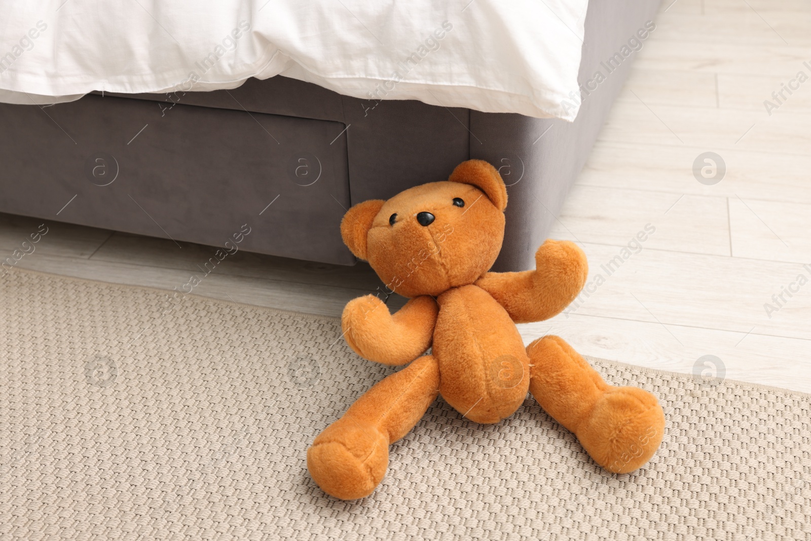 Photo of Lost teddy bear near bed on floor in room