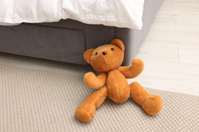 Photo of Lost teddy bear near bed on floor in room