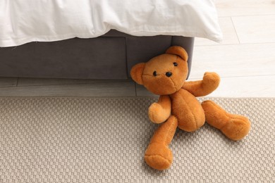 Photo of Lost teddy bear near bed on floor in room