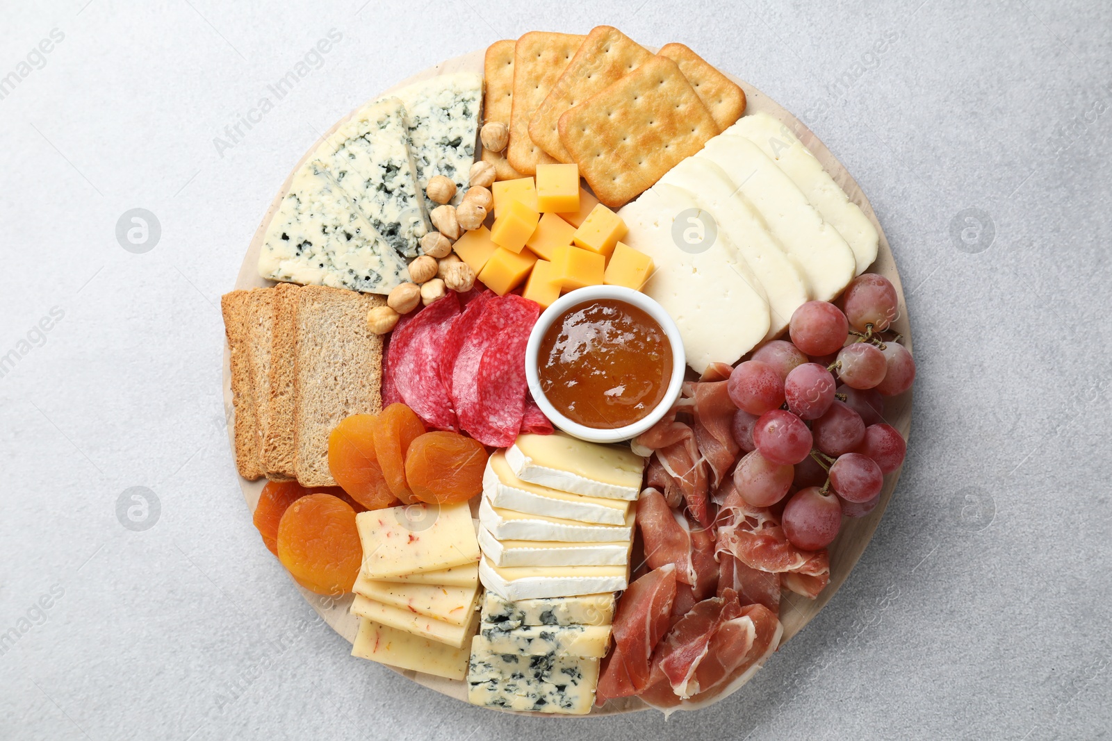 Photo of Different types of cut cheese and other snacks on light textured table, top view