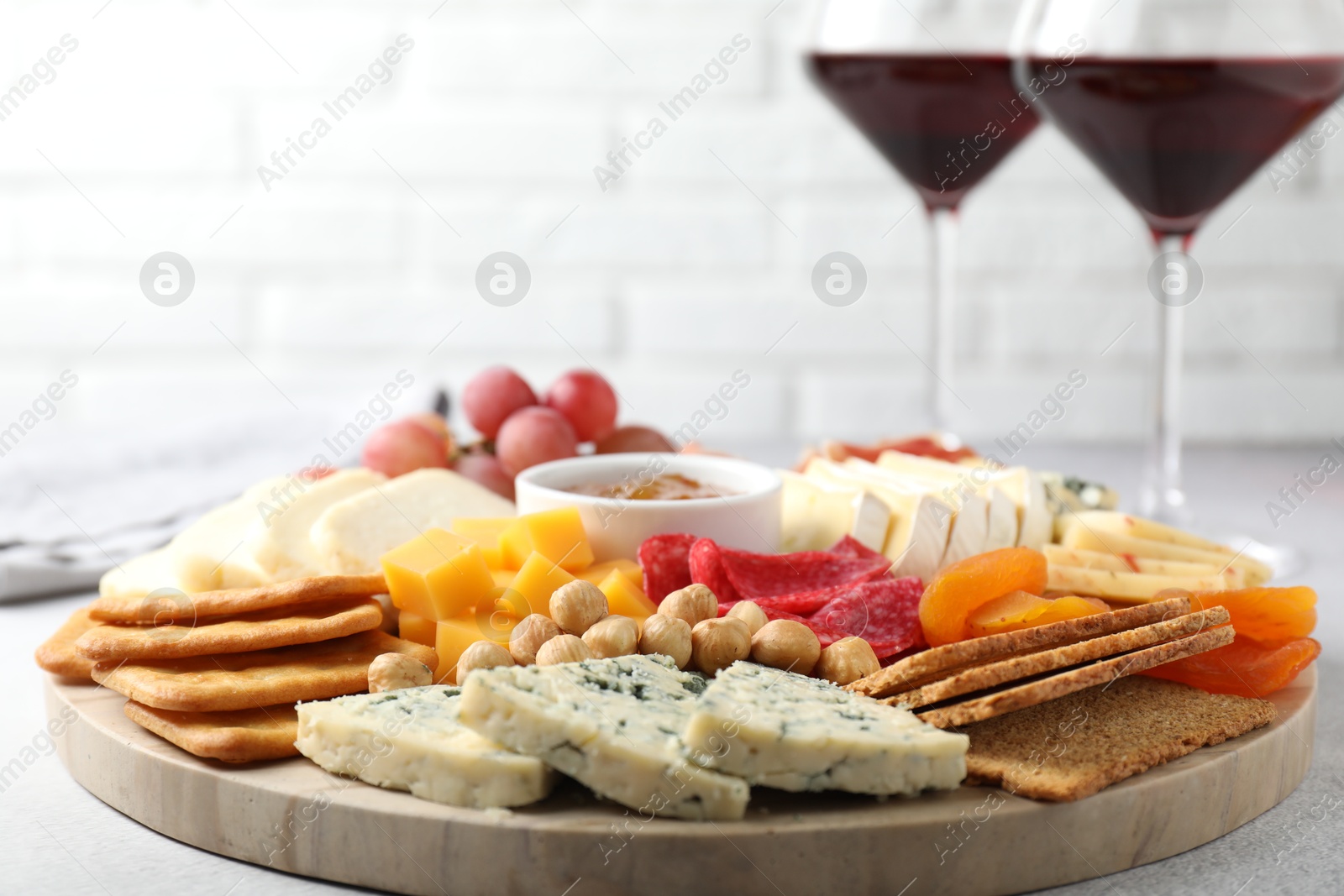 Photo of Different types of cut cheese and other snacks on light textured table, closeup