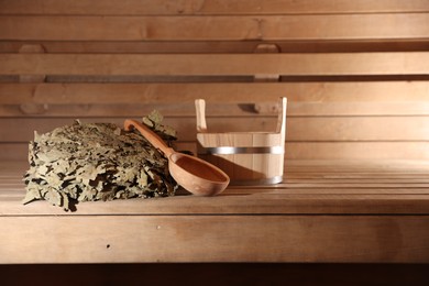 Photo of Bucket, ladle and whisk on wooden bench in sauna