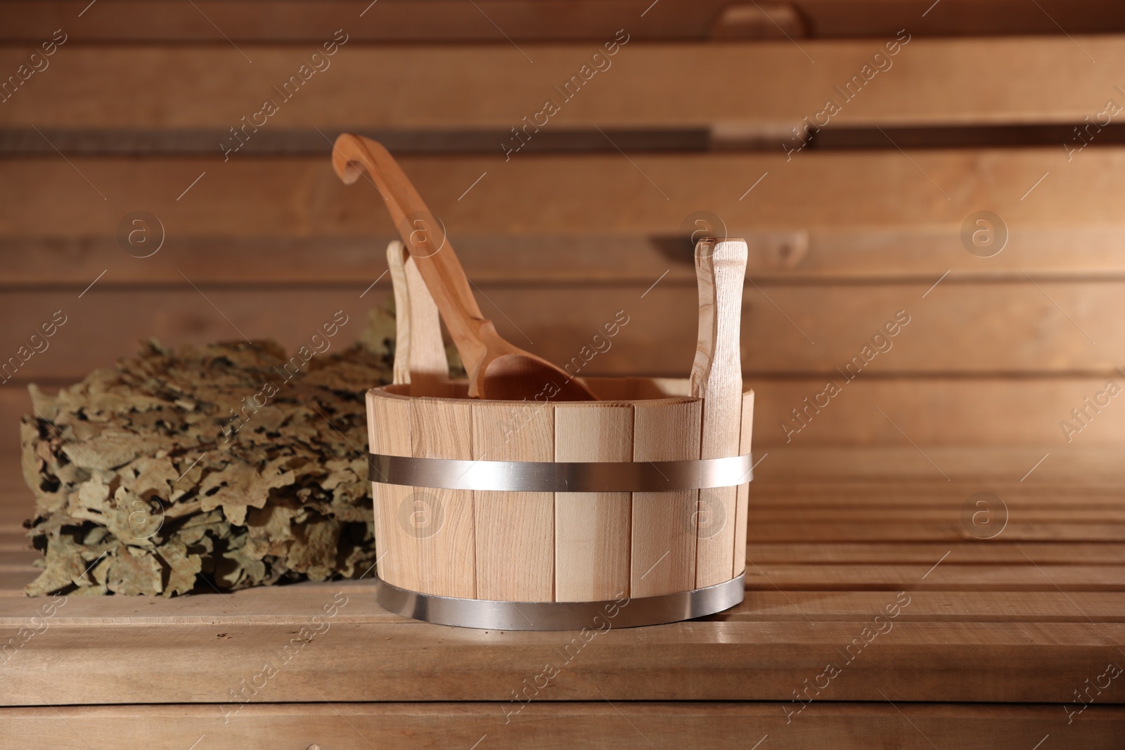 Photo of Bucket, ladle and whisk on wooden bench in sauna