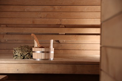 Photo of Bucket, ladle and whisk on wooden bench in sauna. Space for text