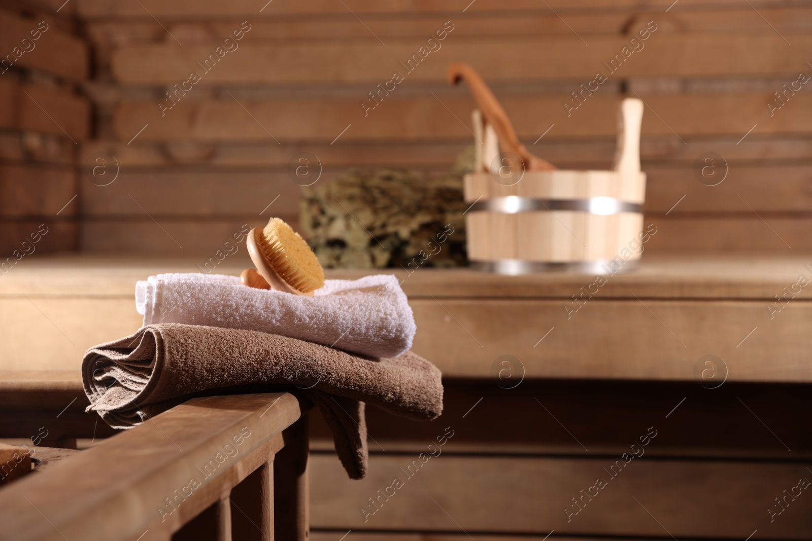 Photo of Massaging brush, stack of towels and other supplies in sauna, selective focus