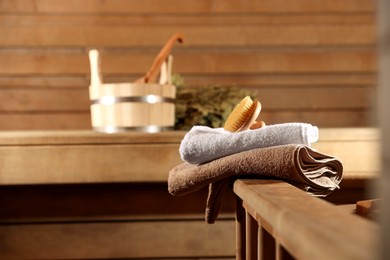 Photo of Massaging brush, stack of towels and other supplies in sauna, selective focus