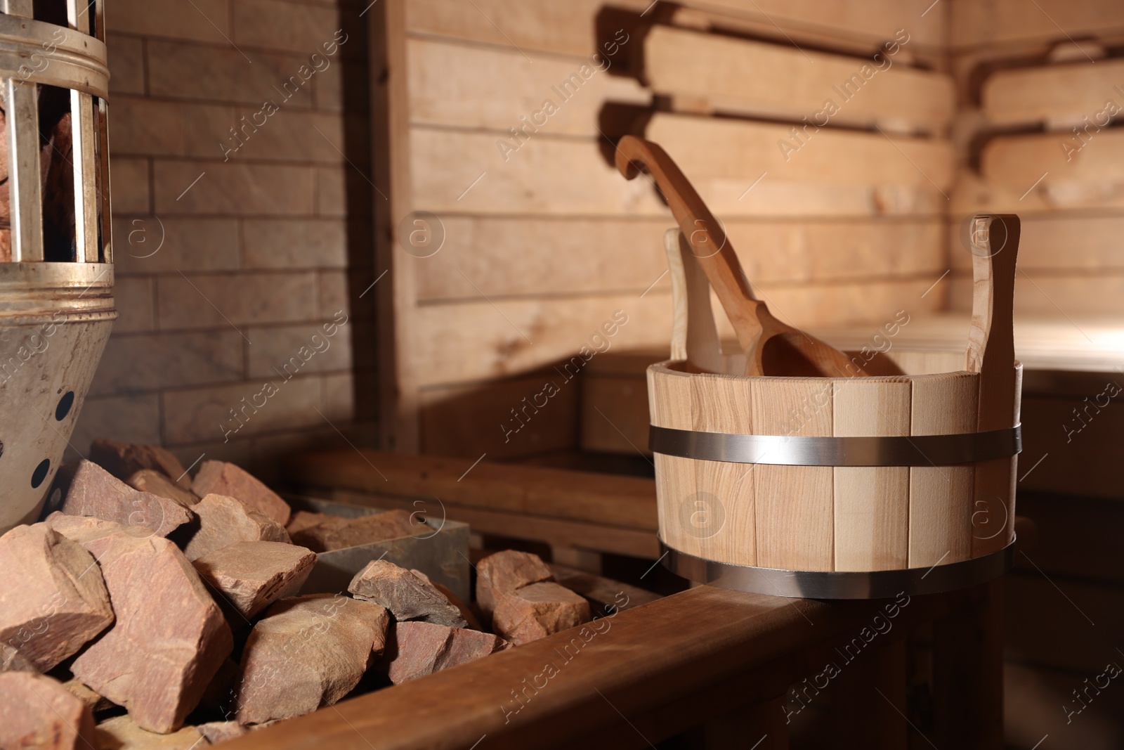 Photo of Bucket, ladle and stove with hot rocks in sauna