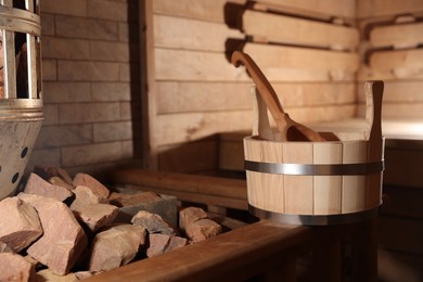 Photo of Bucket, ladle and stove with hot rocks in sauna