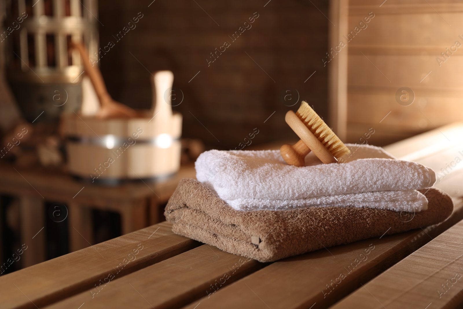 Photo of Massaging brush, stack of towels and other supplies in sauna