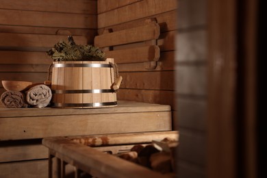 Photo of Bucket, whisk, ladle and towels on wooden bench in sauna