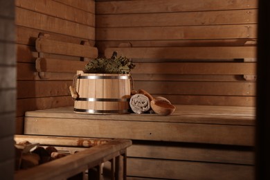 Photo of Bucket, whisk, ladle and towels on wooden bench in sauna