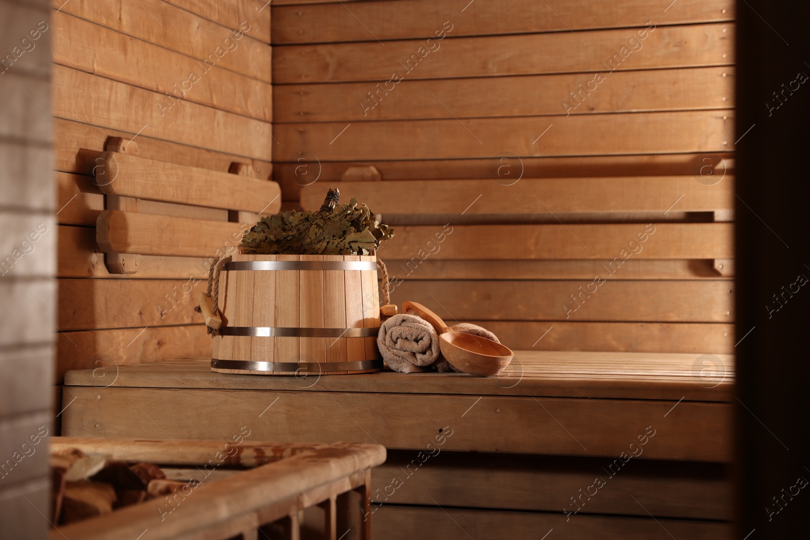 Photo of Bucket, whisk, ladle and towels on wooden bench in sauna