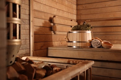 Photo of Bucket, whisk, ladle and towels on wooden bench in sauna