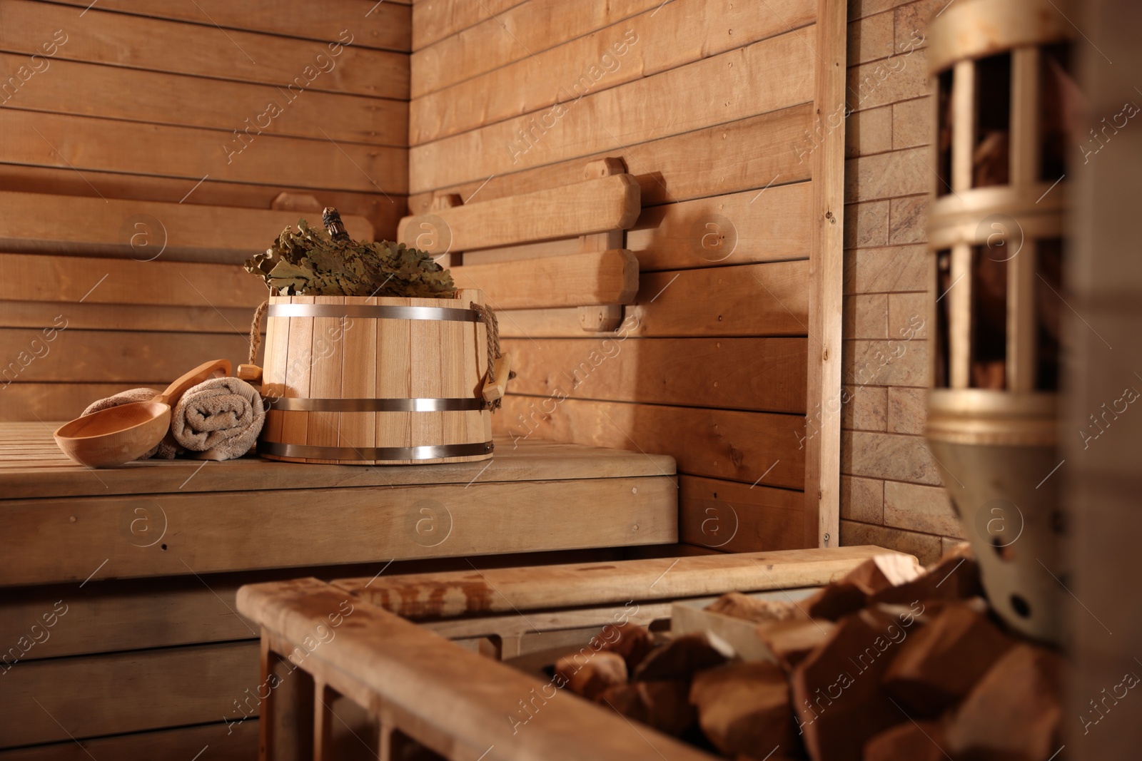 Photo of Bucket, whisk, ladle and towels on wooden bench in sauna