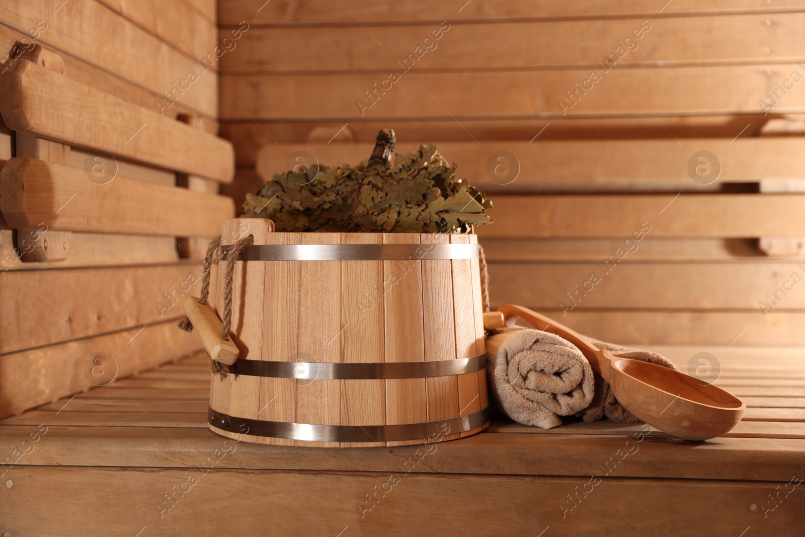 Photo of Bucket, whisk, ladle and towels on wooden bench in sauna