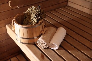 Photo of Bucket, whisk and towels on wooden bench in sauna