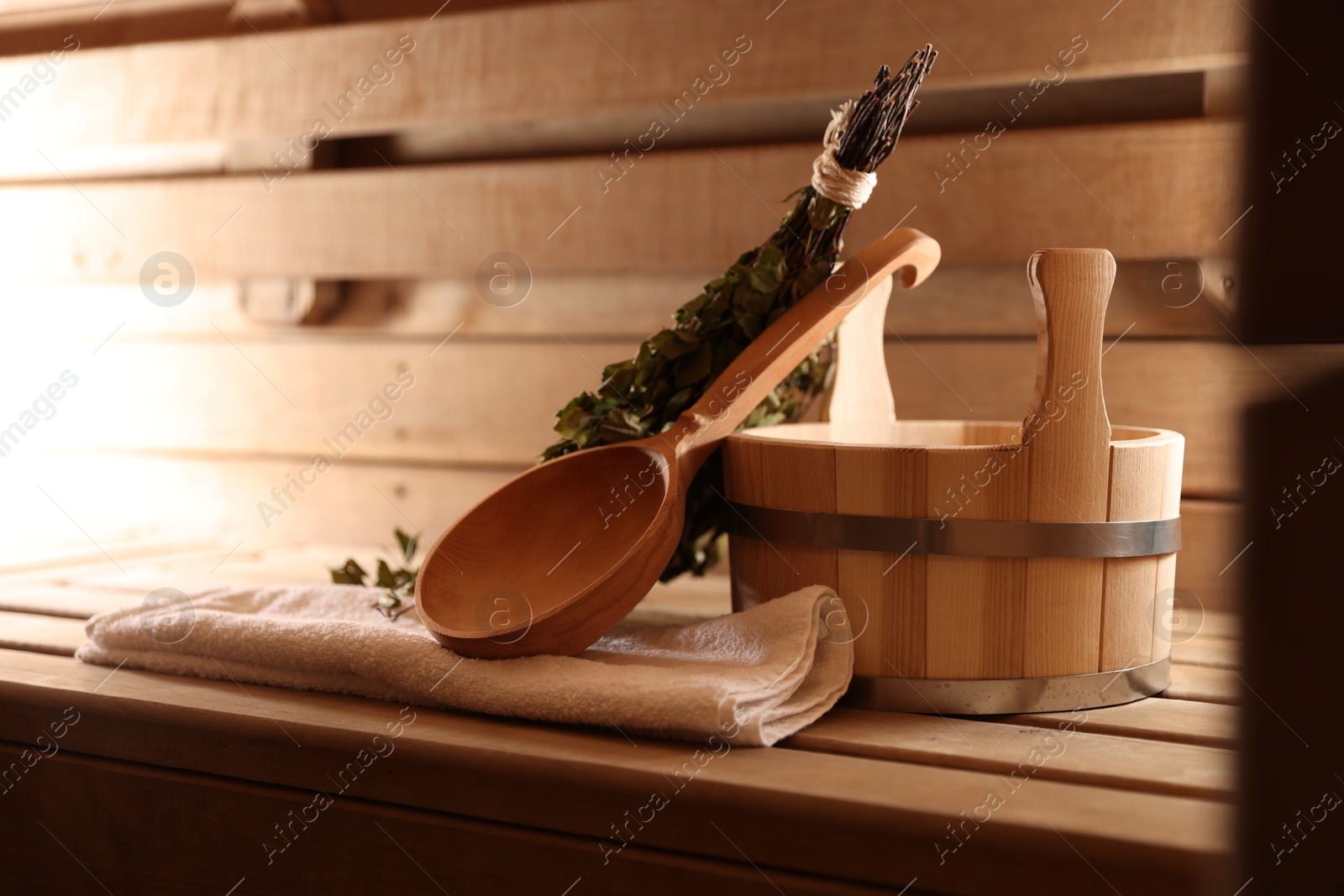 Photo of Ladle, towel, bucket and whisk on wooden bench in sauna