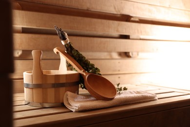 Photo of Ladle, towel, bucket and whisk on wooden bench in sauna