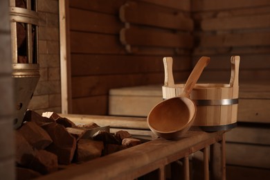 Bucket, ladle and stove with hot rocks in sauna