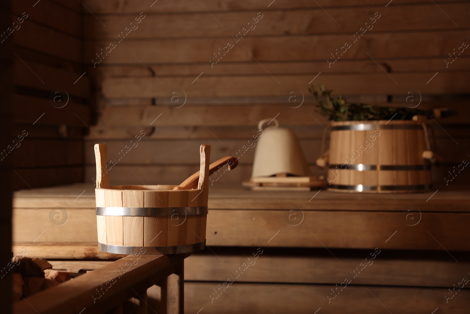 Photo of Bucket, ladle and other supplies in sauna, selective focus