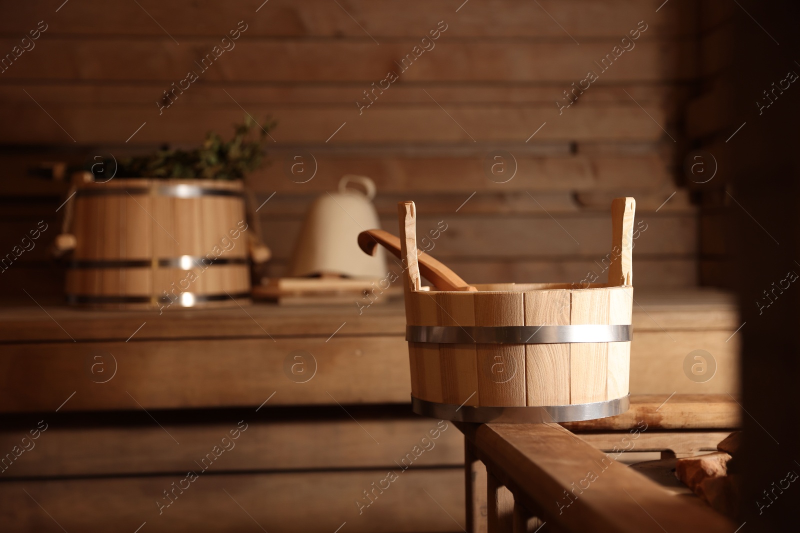 Photo of Bucket, ladle and other supplies in sauna, selective focus