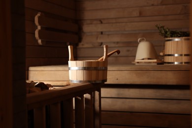 Photo of Bucket, ladle and other supplies in sauna, selective focus