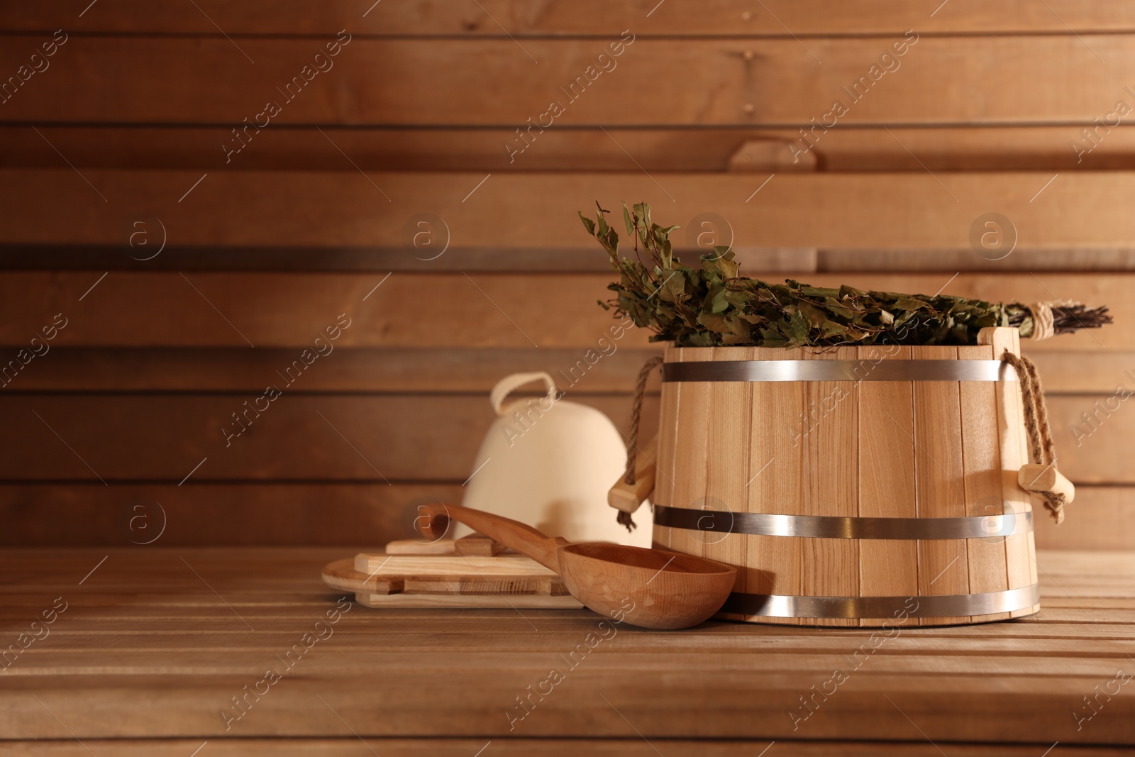 Photo of Bucket, ladle and whisk on wooden bench in sauna. Space for text