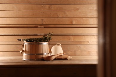 Photo of Bucket, ladle and whisk on wooden bench in sauna. Space for text