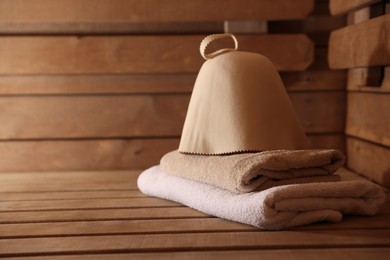 Photo of Hat and towels on wooden bench in sauna. Space for text